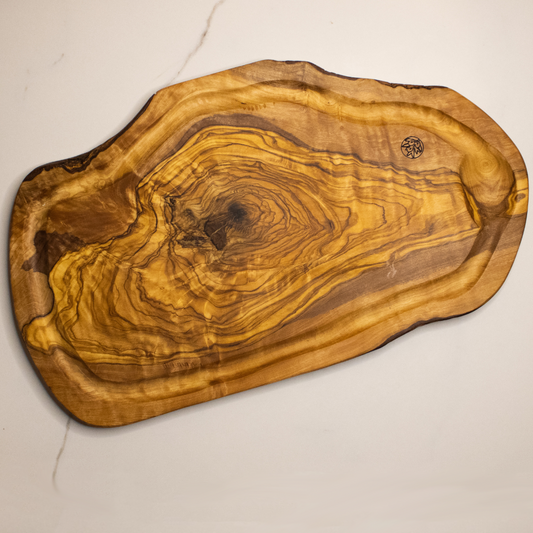 Planche avec rainures à jus en bois d&#39;olivier posé sur une table en marbre