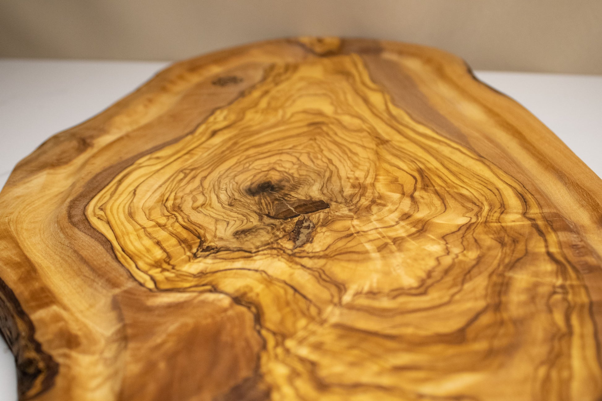 Planche avec rainures à jus en bois d&#39;olivier posé sur une table en marbre